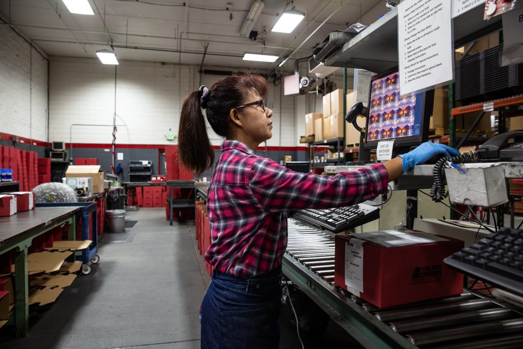 Copyrighted 2018 Ken Cooper | A woman in a plaid shirt works on a computer in the factory at Helwig Carbon
